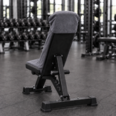 Charcoal grey hooded gym towel fitted securely over an incline bench, rear view